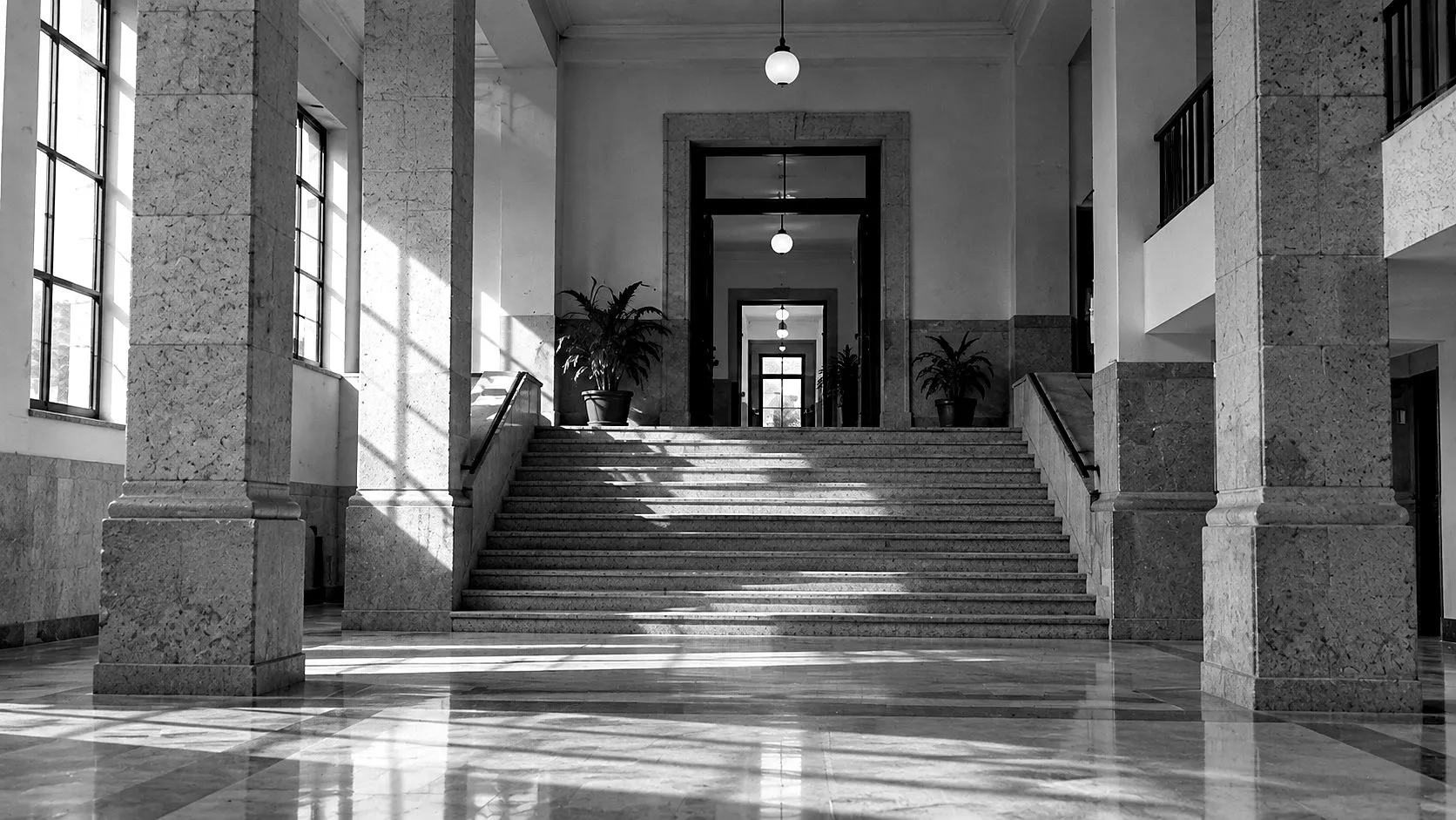 Interior de un edificio institucional, con columnas de mármol y una escalinata amplia.